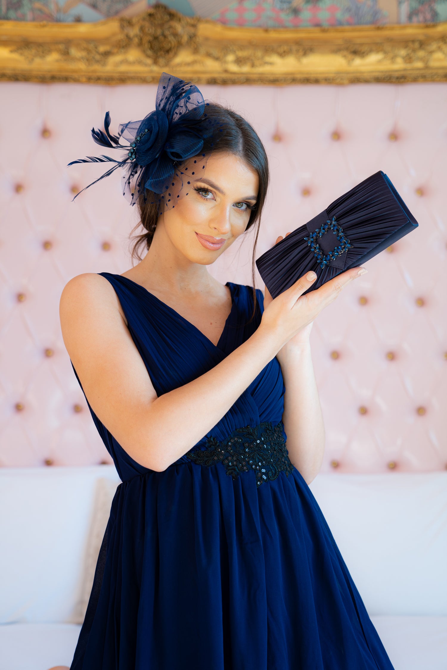 A BEAUTIFUL LADY DRESSED IN BLUE DRESS, BLUE SATIN BAG AND BLUE FASCINATOR